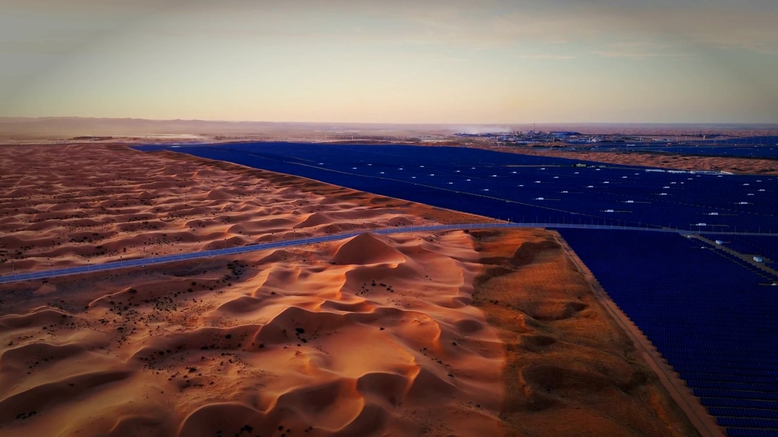 Aerial view of a large solar plant beside desert dunes, a frame from Twenty-Five Summers on solar panel recycling in India